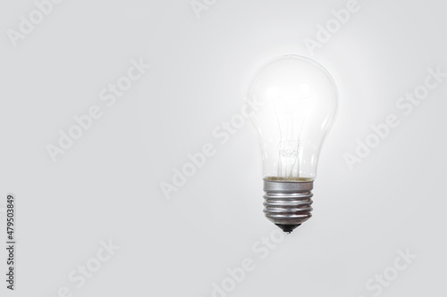 A glowing light bulb on a gray background, a place for text