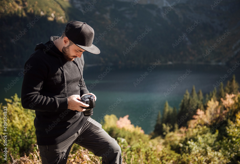 Obraz premium Young man photographer taking photographs with digital camera in a mountains.
