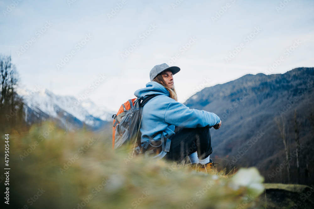 Man with backpack sitting with eyes closed on mountain Man with backpack sitting with eyes closed on mountain