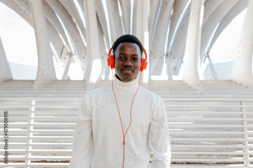 Smiling young man wearing orange colored headphones photo