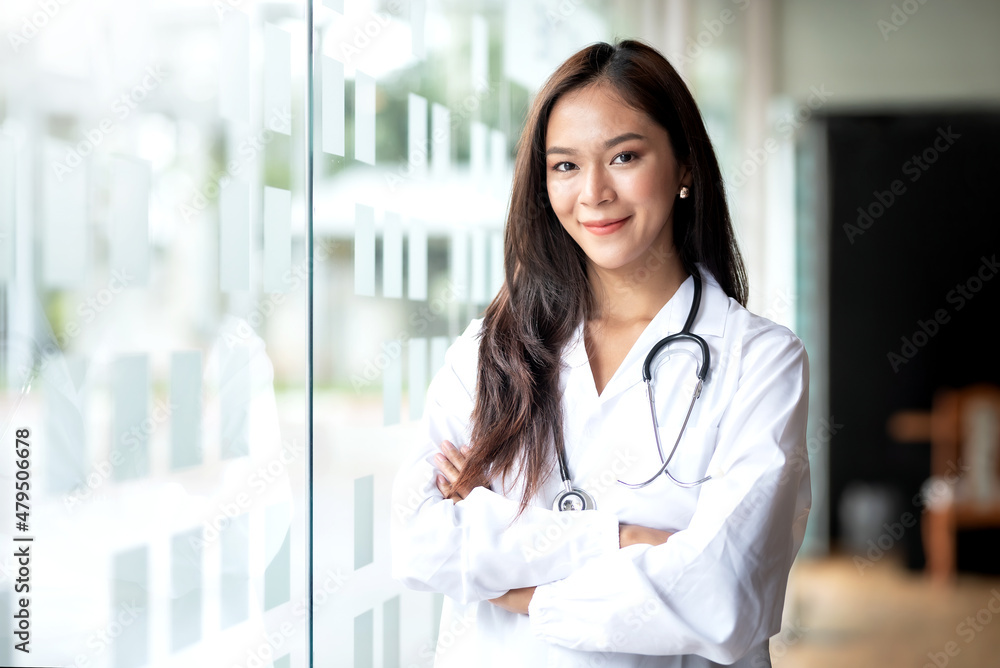 Smiling Asian female doctor in lab coat with arms crossed against looking at camera. Smiling Asian female doctor in lab coat with arms crossed against looking at camera.