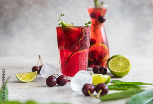 Cocktail or lemonade with cherries and lime, grey stone background. Mocktail. Cold summer drink.