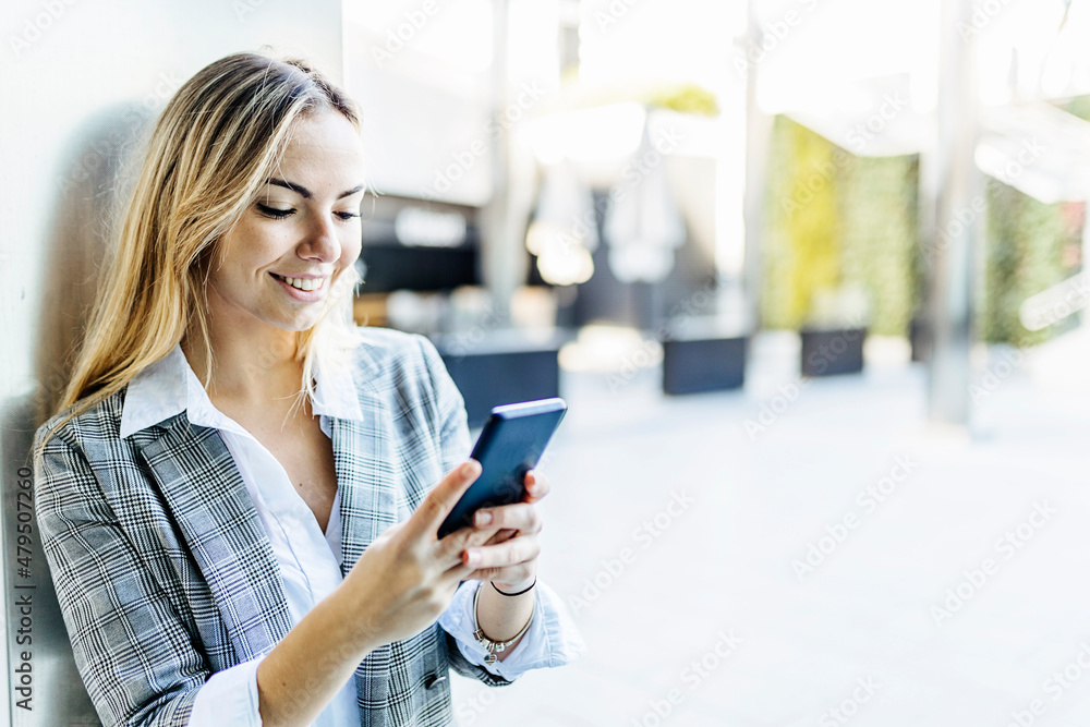 Smiling businesswoman text messaging on mobile phone Smiling businesswoman text messaging on mobile phone
