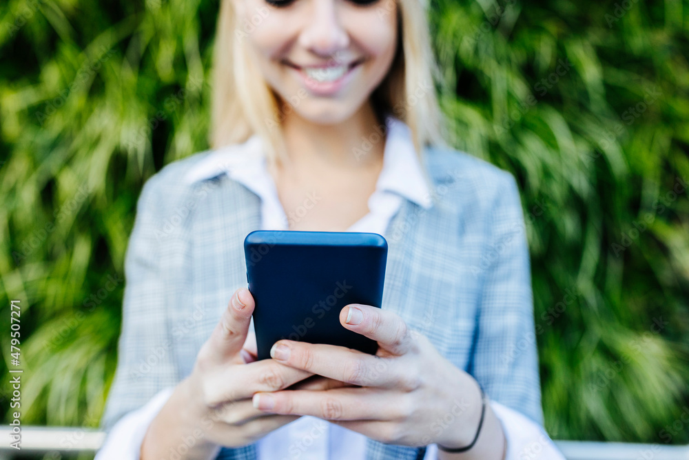 Smiling businesswoman text messaging through smart phone Smiling businesswoman text messaging through smart phone