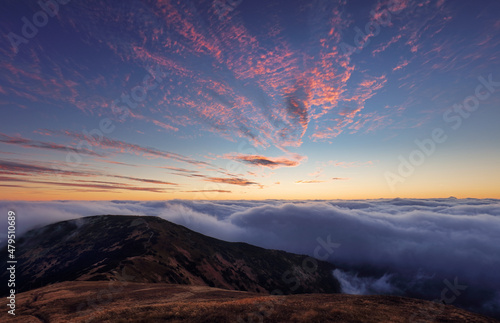 Fabulous sunset high in the mountains above the clouds. Aerial view of dramatic mountain landscape at dusk with fog and soft light.