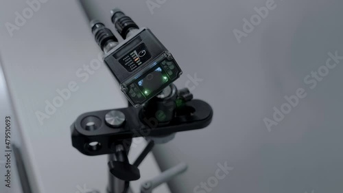 An industrial laser sensor on a conveyor detects the passage of a white plastic containers, detects it and enters into a database. Closeup