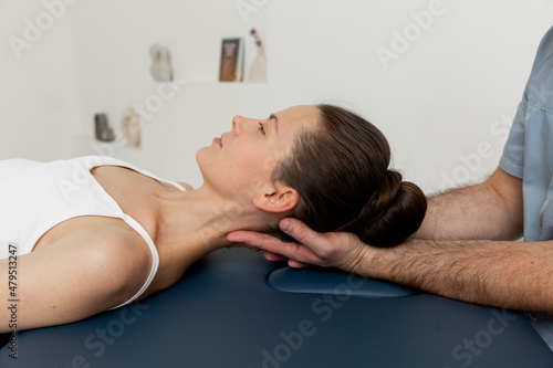 Female patient receiving osteopathic neck and shoulder treatment. Therapist manipulating back of head and chest. A girl receiving CST treatment. Osteopathic manipulation and therapy