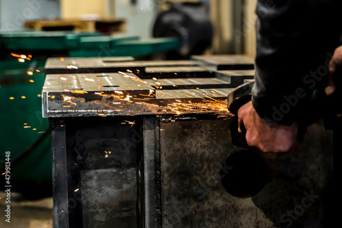 Grinding burrs and metal with an angle grinder with sparks.