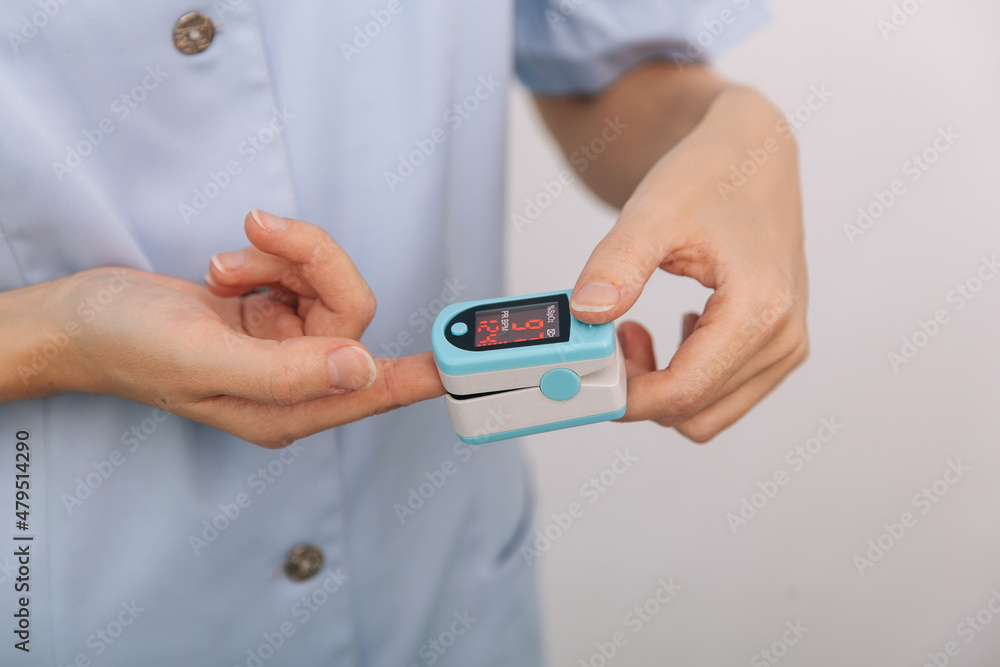 Pulse oximeter with hand of doctor isolated on white. The concept of portable digital device to measure person's oxygen saturation. Measuring oxygen saturation, pulse rate and oxygen levels. Pulse oximeter with hand of doctor isolated on white. The concept of portable digital device to measure person's oxygen saturation. Measuring oxygen saturation, pulse rate and oxygen levels.
