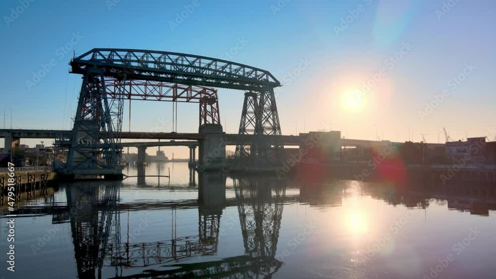 Sunrise view of the historic monument of Puente Transbordador Nicolas Avellaneda bridge with beautiful refection on Riachuelo river, low level aerial stationary shot. Sunrise view of the historic monument of Puente Transbordador Nicolas Avellaneda bridge with beautiful refection on Riachuelo river, low level aerial stationary shot.