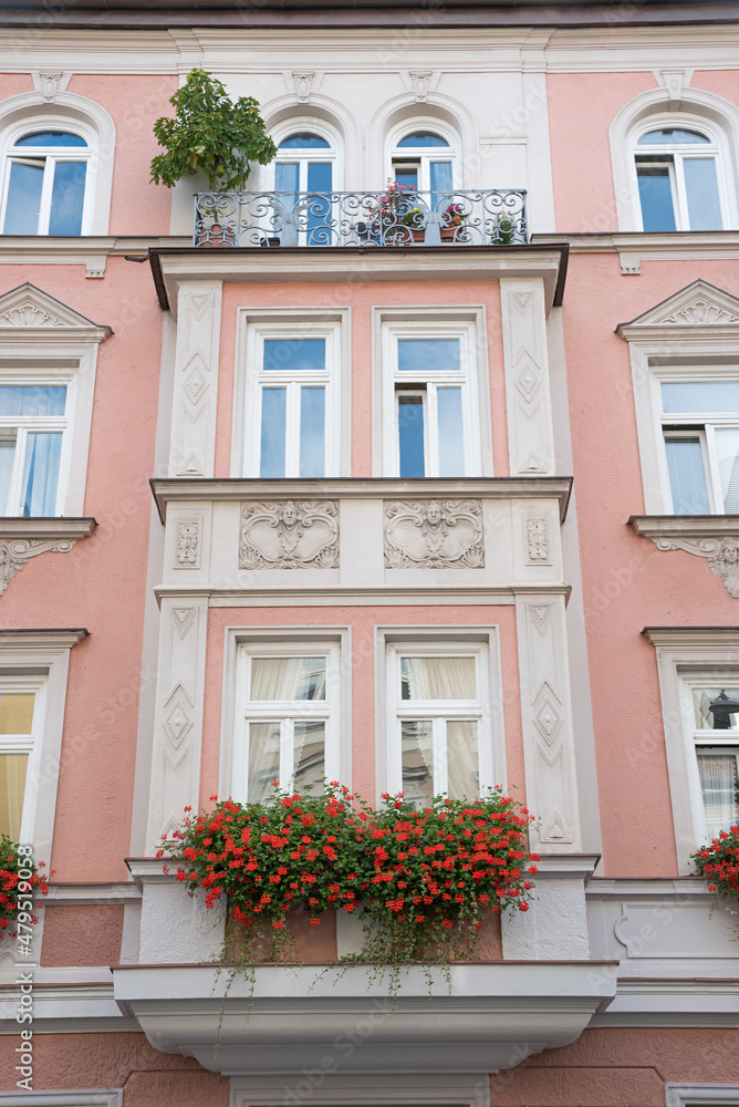 historic house facade munich, with balcony, jutties and geranium flowers