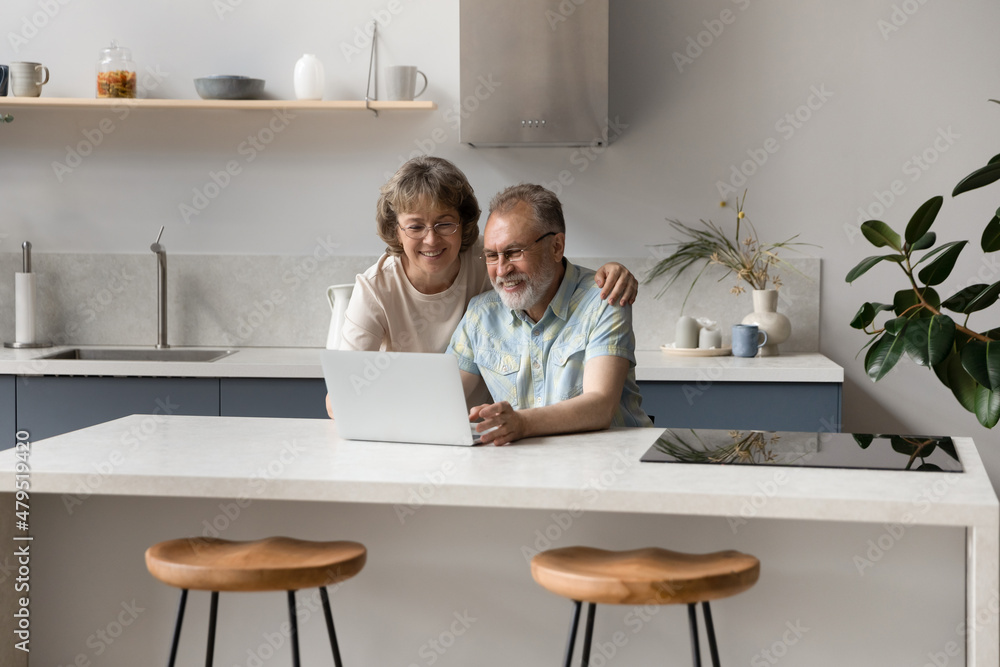 Addicted to modern technology smiling old middle aged couple using computer apps, enjoying choosing goods shopping in internet store, reading email with pleasant news, web surfing information online. Addicted to modern technology smiling old middle aged couple using computer apps, enjoying choosing goods shopping in internet store, reading email with pleasant news, web surfing information online.