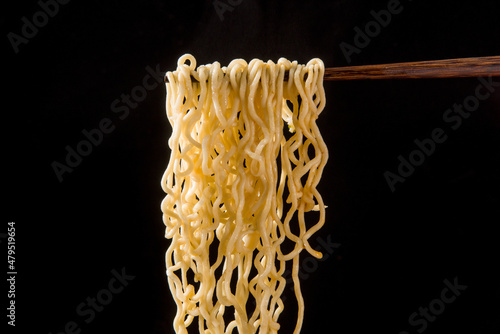 chopsticks with cooked instant noodles on black background