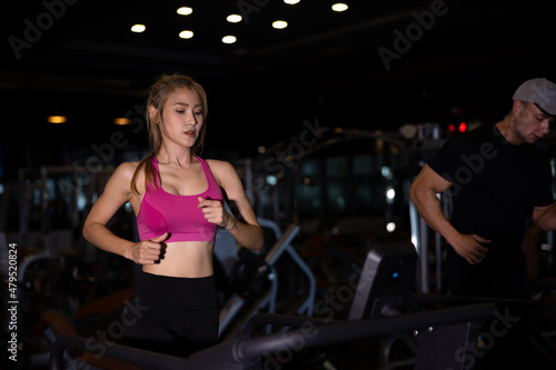 couple young women asian and white man walking and running in a gym on a treadmill.exercising concept.fitness healthy lifestyle cinematic dark tone