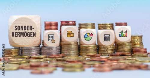 Sondervermögen. Münzstapel mit Holzwürfeln. Text und Icons auf Würfel