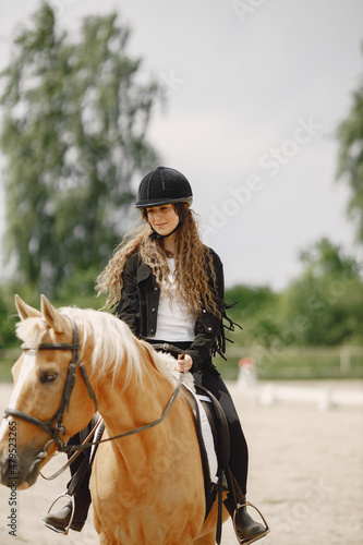 Portrait of woman in black helmet riding a brown horse © hetmanstock2