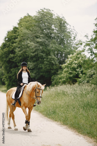 Portrait of woman in black helmet riding a brown horse