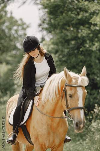 Portrait of woman in black helmet riding a brown horse