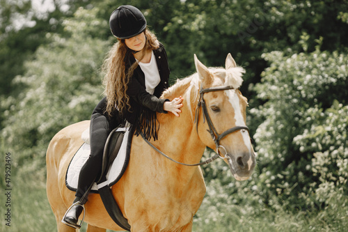 Portrait of woman in black helmet riding a brown horse © hetmanstock2