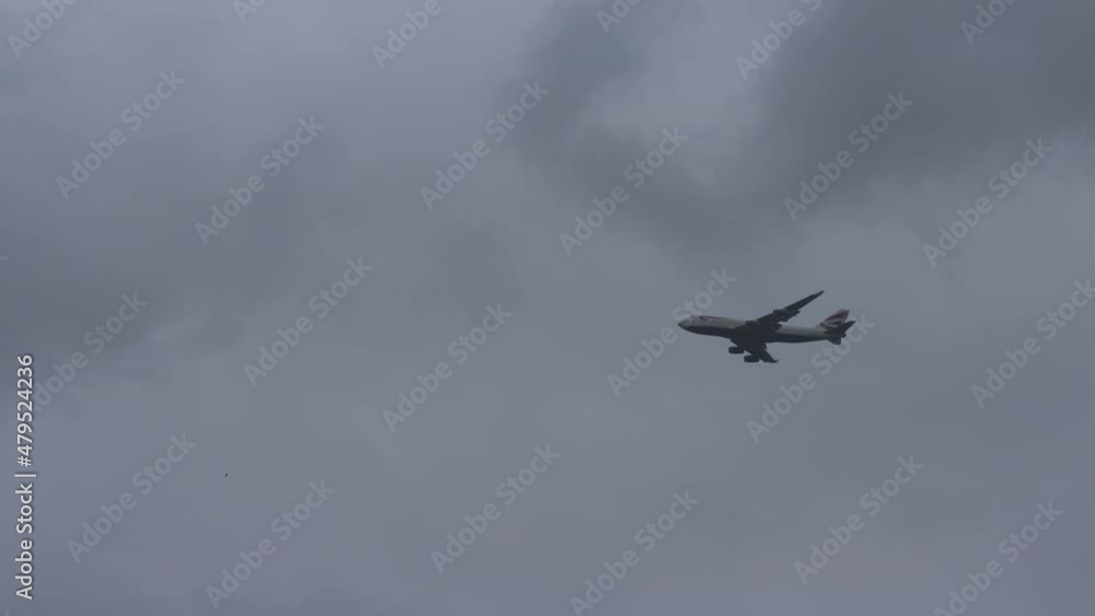 looking up at Boing 747 passenger jet plane flying through dark clouds in sky. looking up at Boing 747 passenger jet plane flying through dark clouds in sky.