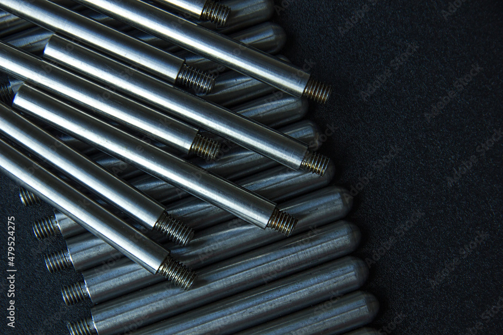 The turned parts on the production table in a row against a dark background. The manufacture of axles in the factory. The turned parts on the production table in a row against a dark background. The manufacture of axles in the factory.