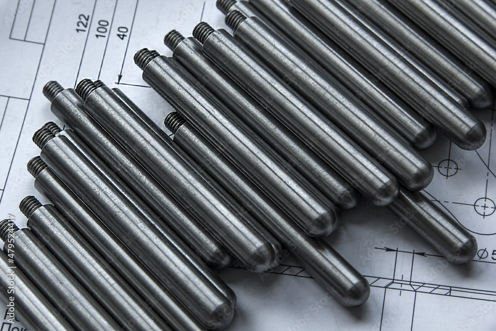 The turned parts on the production table lie in a row on the drawings. The manufacture of axles in the factory. The turned parts on the production table lie in a row on the drawings. The manufacture of axles in the factory.