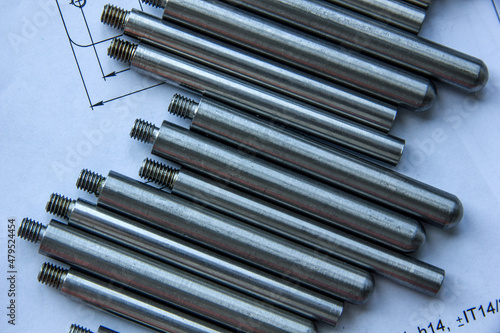 The turned parts on the production table lie in a row on the drawings. The manufacture of axles in the factory.