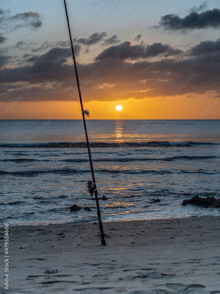 Fishing rod waiting in the sand as the goes down Fishing rod waiting in the sand as the goes down