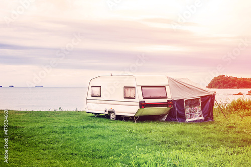 Trailer home and a tent by the grass lake shore. Adventure relaxing travel on caravan van and camping home
