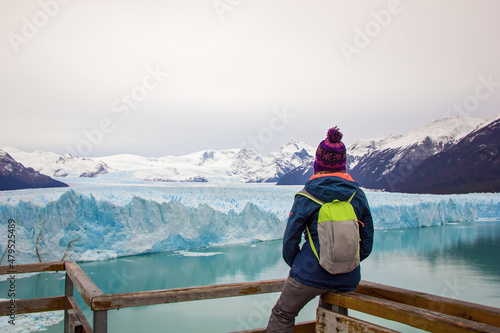 Young woman, girl with backpack looks at Perito Moreno glacier in Patagonia. Floe located in Los Glaciares National Park, in the southwest of the Argentine province of Santa Cruz, El Calafate photo