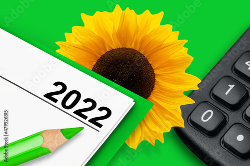 Kalender 2022 Finanzen Klimaschutz mit Sonnenblume und Rechner auf grünem Hintergrund photo