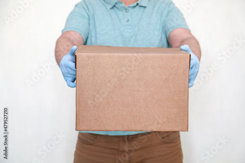 Parcel delivery. Courier in gloves and with a cardboard box for a customer close up. A man with a parcel in his hands. photo