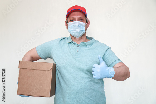 Parcel delivery. Courier in gloves and a mask with a box for a customer. A man with a parcel in his hands. photo