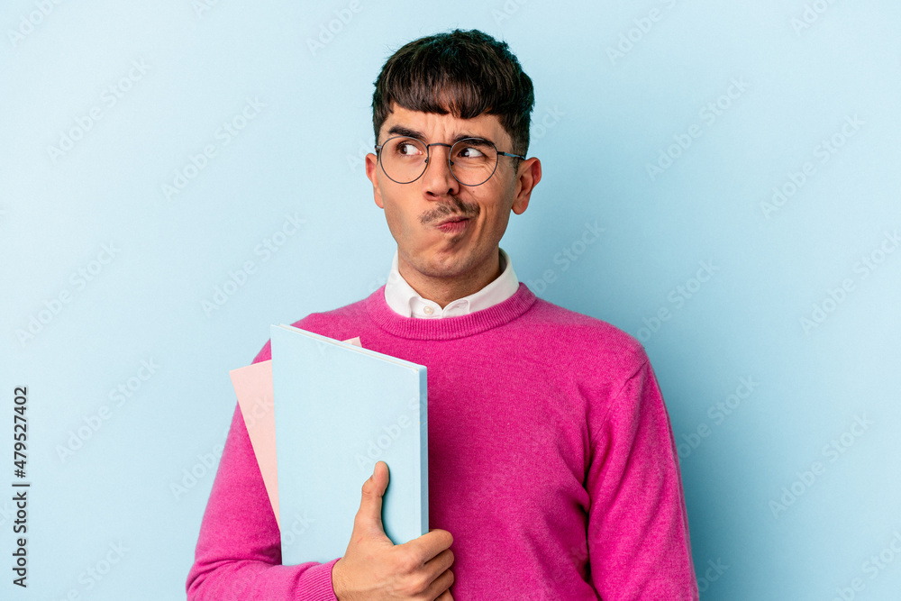 Young mixed race student man isolated on blue background confused, feels doubtful and unsure. Young mixed race student man isolated on blue background confused, feels doubtful and unsure.