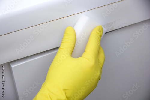 A gloved hand rubs a melamine sponge over the bathroom. Cleaning concept photo