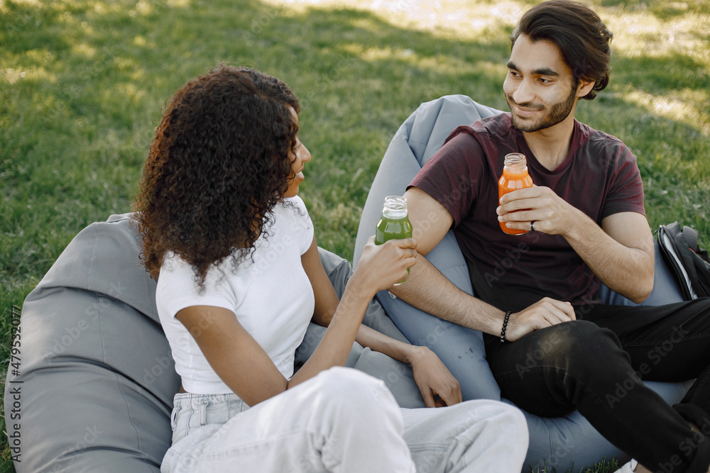 Indian boy and african girl talking sitting on the bean bag chairs in a ...