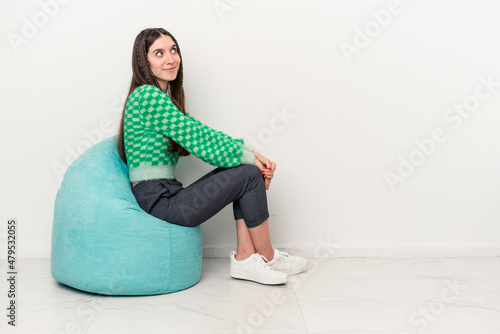 Young caucasian woman sitting on a puff isolated on white background
