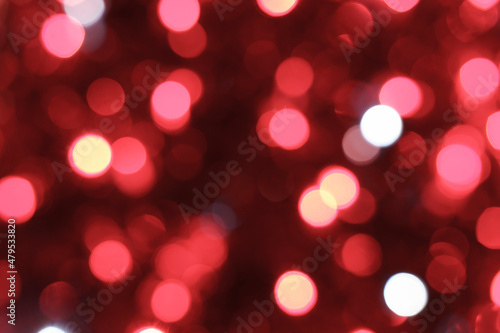 Red bokeh background. Texture foil and blurred confetti, light of golden dust. Festive party Christmas and new year's eve background.