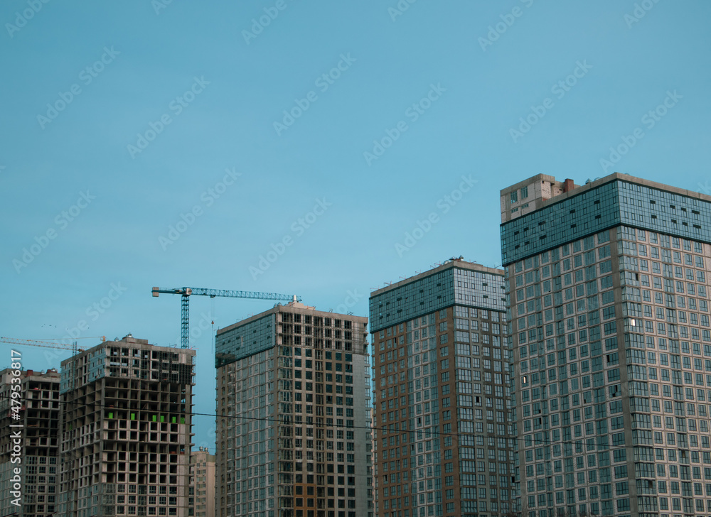Kyiv, Ukraine. January 8, 2022. Modern high residential multistory apartment building with glass facade against a blue sky with space for text. Monochrome cityscape. Urban scene. Modern architecture. Kyiv, Ukraine. January 8, 2022. Modern high residential multistory apartment building with glass facade against a blue sky with space for text. Monochrome cityscape. Urban scene. Modern architecture.