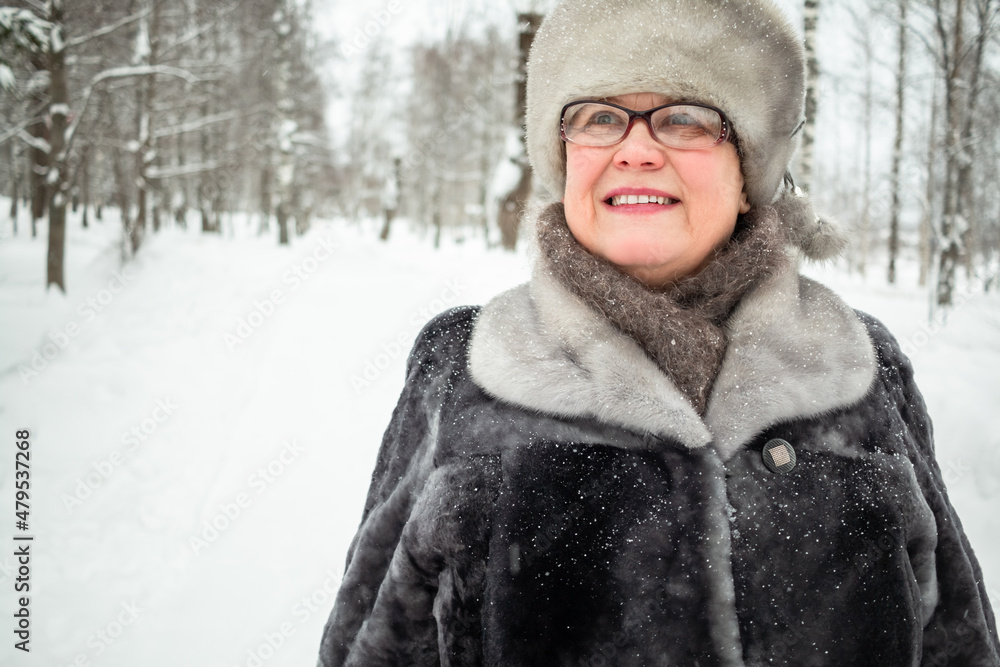 An elderly woman walks in a winter city park. An elderly woman walks in a winter city park.