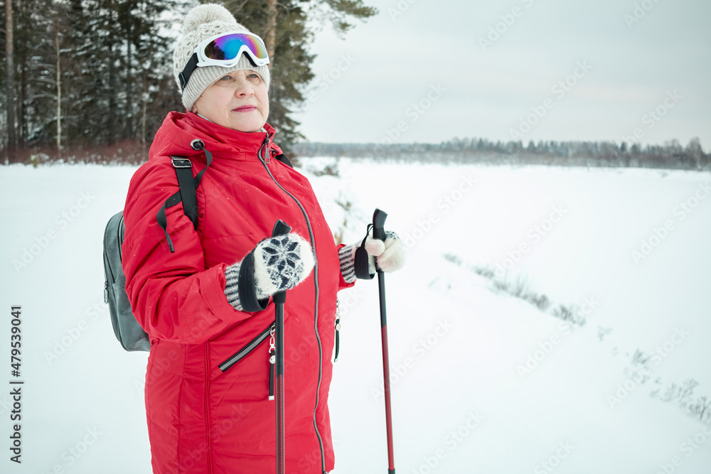 An elderly woman goes in for sports. Nordic walking in winter.