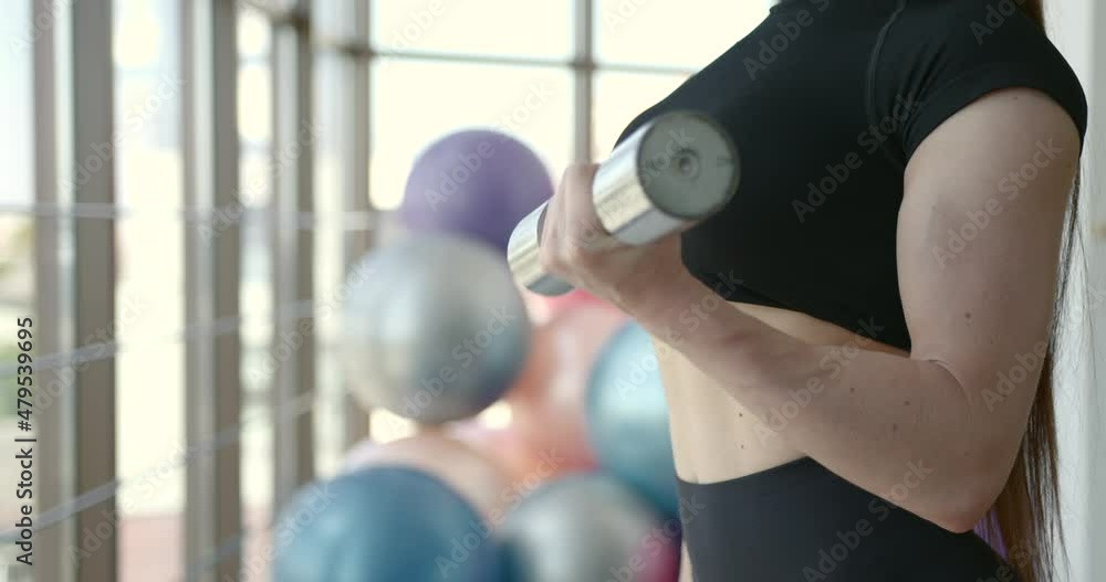 Fit girl in black uniform with dumbbells near window Fit girl in black uniform with dumbbells near window