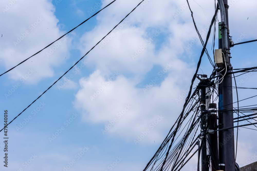electric and telecommunication poles with messy cables stand under the bright blue sky electric and telecommunication poles with messy cables stand under the bright blue sky