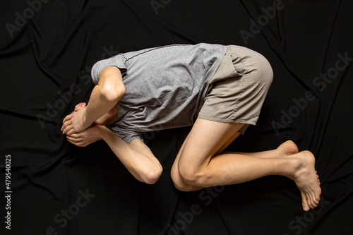 A depressed man on a black background is holding his head. Mental health.