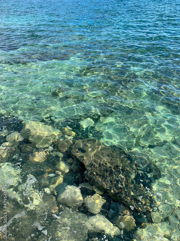 Transparent sea surface, lagoon, pebbles and stones, ripples on the sea surface