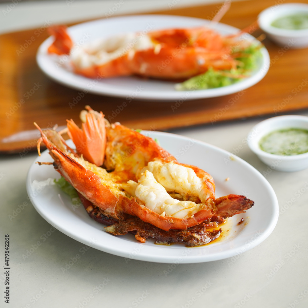 Grilled river prawn. Fine dining of a charcoal grilled lobster with soft focus served with seafood sauce on the mini bowl. Grilled river prawn. Fine dining of a charcoal grilled lobster with soft focus served with seafood sauce on the mini bowl.
