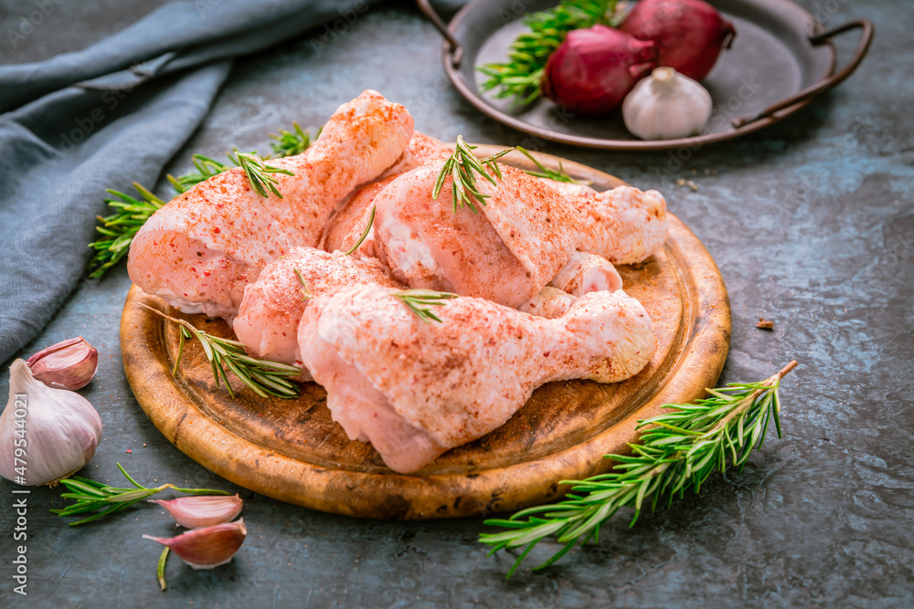 Raw uncooked chicken legs, drumsticks on wooden board, meat with ingredients for cooking Raw uncooked chicken legs, drumsticks on wooden board, meat with ingredients for cooking