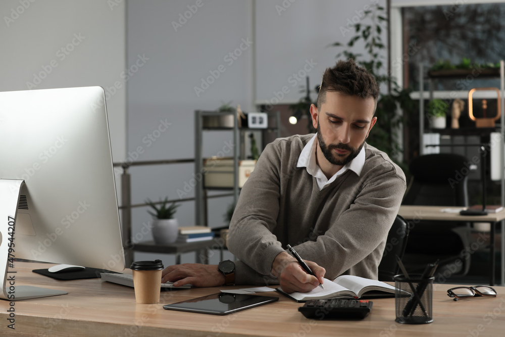 Man with notebook working at table in office Man with notebook working at table in office