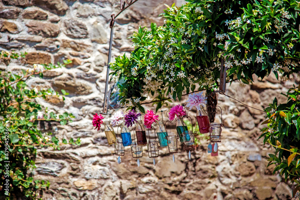 Flowers in jars in the middle of the street against the background of jasmine flowers and a stone wall