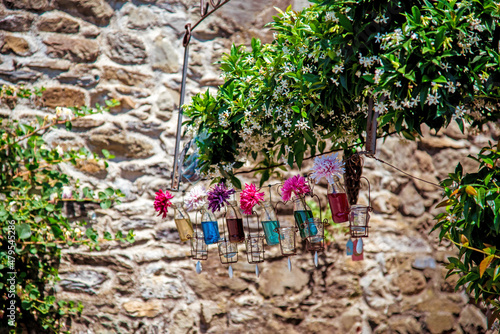 Obraz na płótnie Flowers in jars in the middle of the street against the background of jasmine flowers and a stone wall w salonie